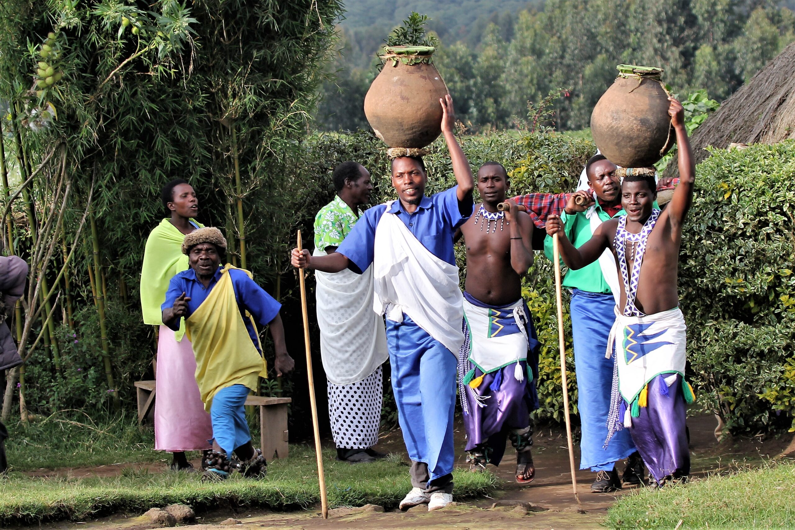 What month is the best time to visit Rwanda featured image: Rwandan villagers in traditional attire carrying clay pots at Ibyiwacu Cultural Village